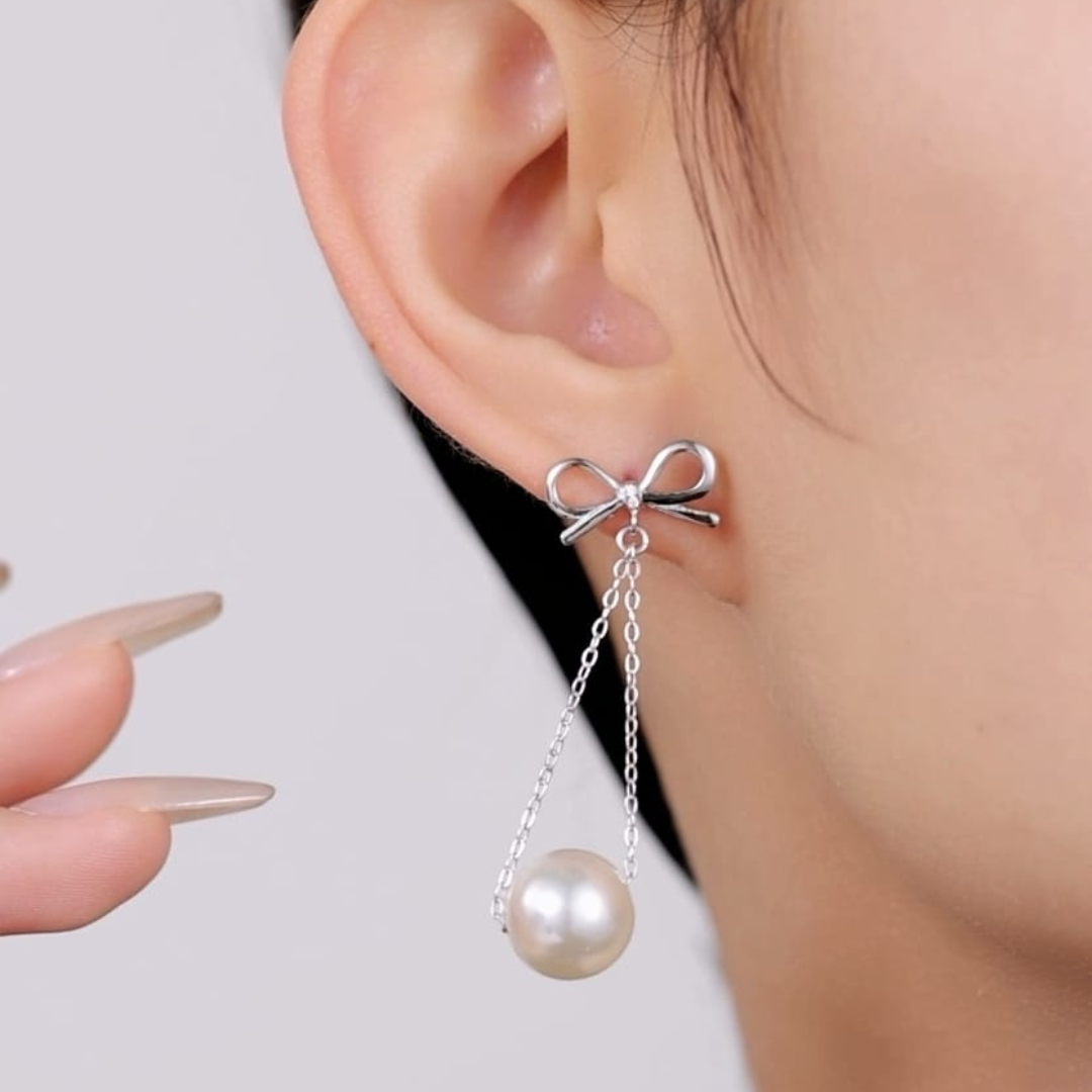 Close-up of a woman's ear showcasing the Bow Pearl Earring, featuring a lustrous pearl and chic design, made of pure 925 Sterling Silver.