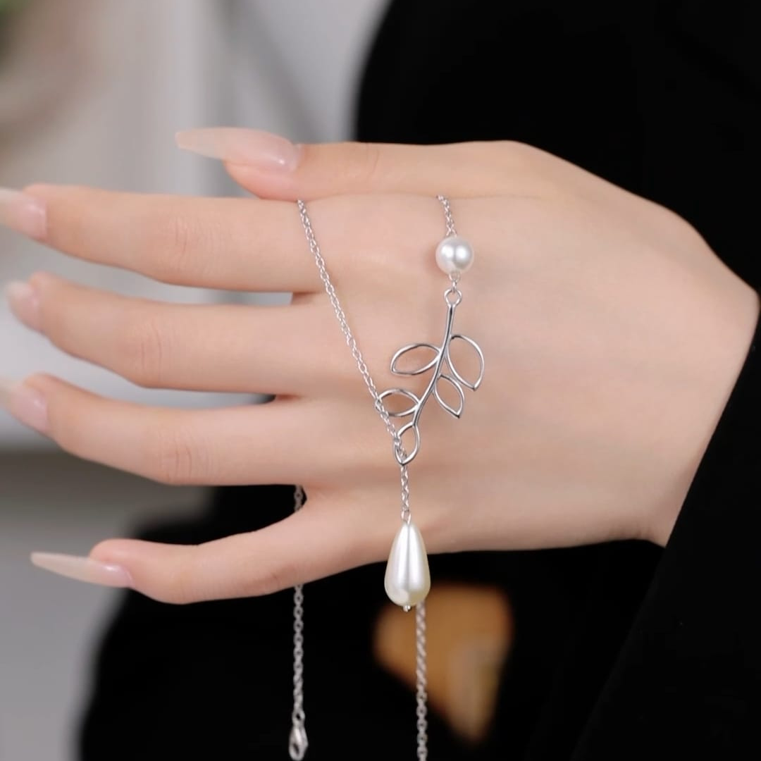 A hand adorned with the Pearl N Leaf bracelet, showcasing lustrous pearls and delicate leaf motifs.