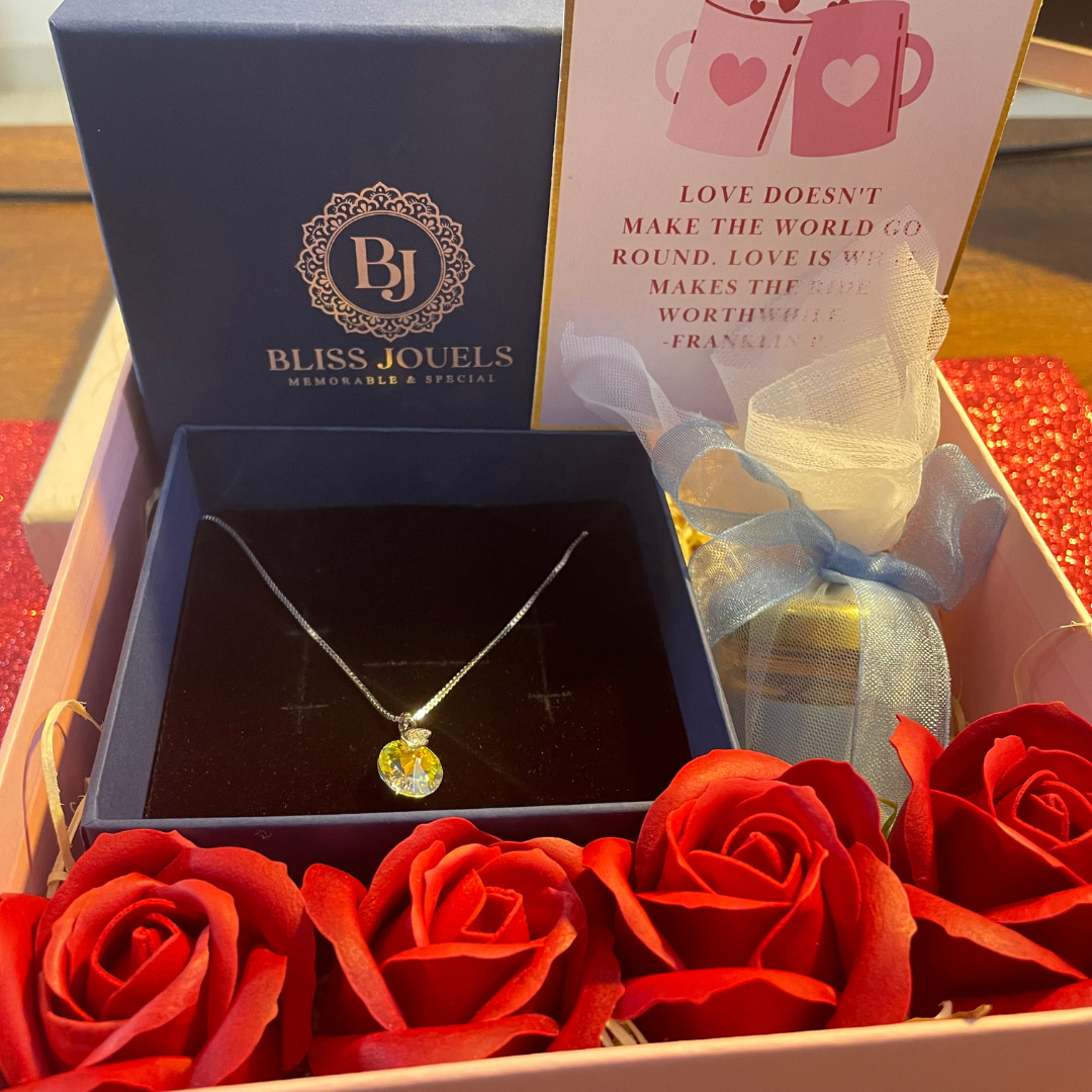 Valentine Hamper featuring a necklace in a box with roses, a handwritten note, a scented candle, and two chocolates.