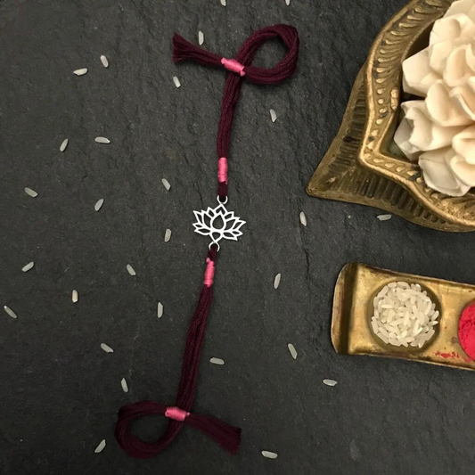 Handcrafted Lotus Rakhi featuring a delicate lotus charm on maroon and pink threads, symbolizing purity and beauty for Raksha Bandhan.