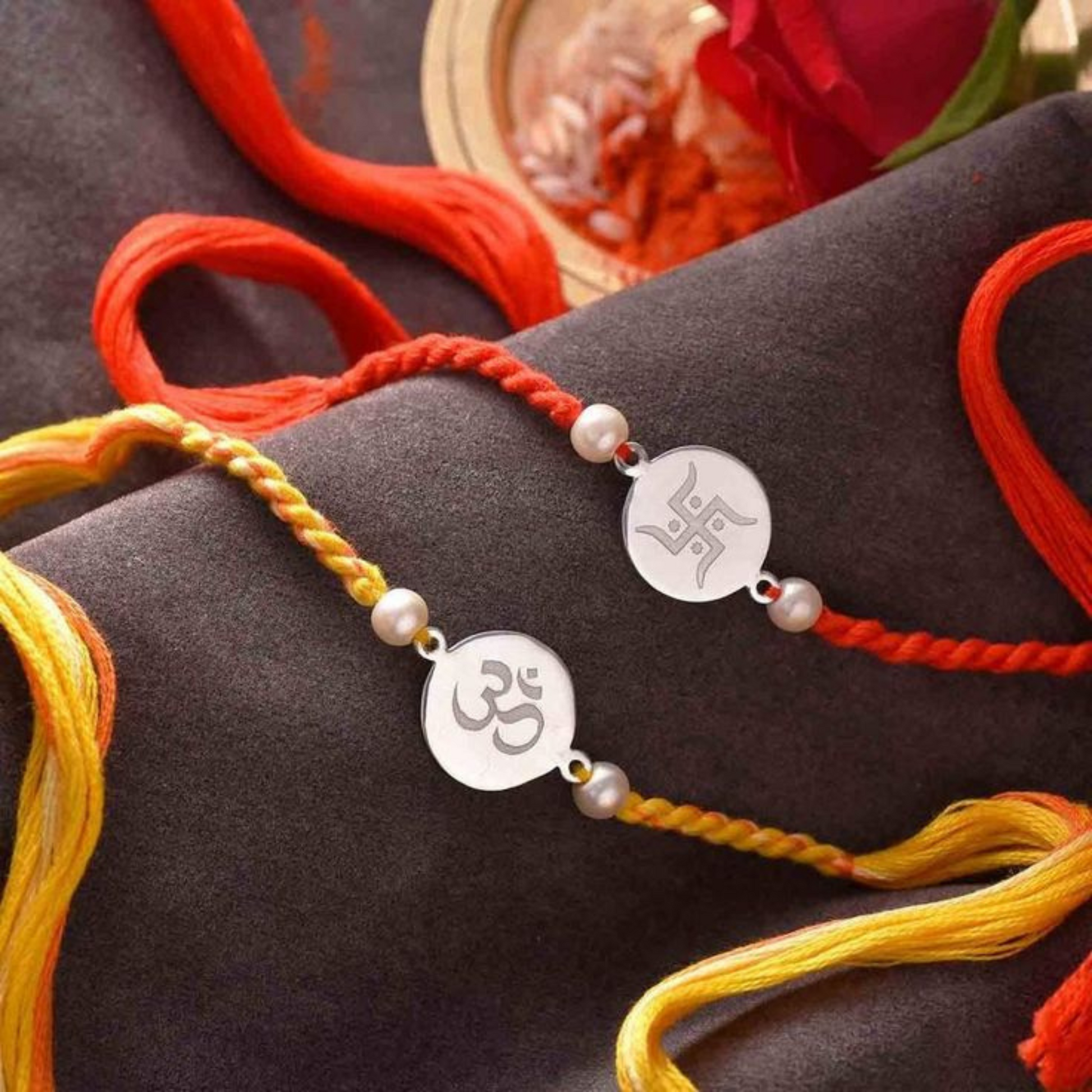 Bliss Jouels Handcrafted Om Rakhi with silver-toned Om discs, pearl embellishments, and colorful threads on a black surface.