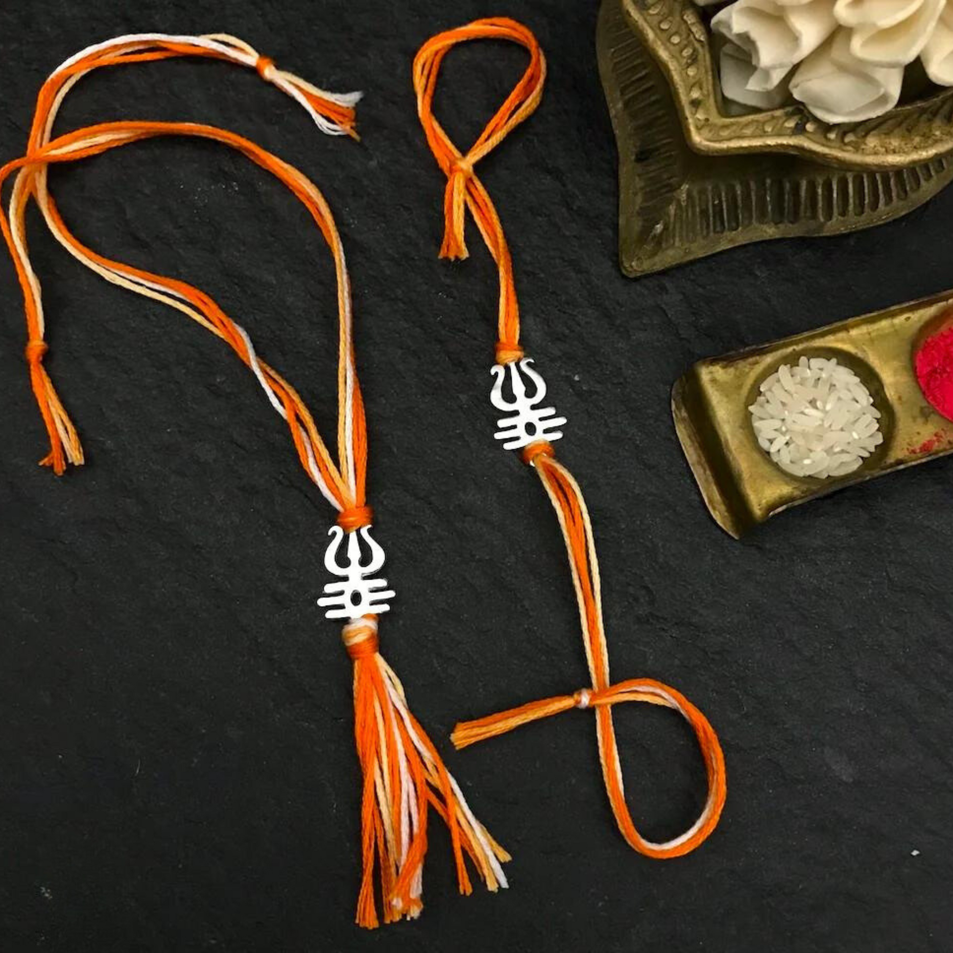 Bliss Jouels Handcrafted Shiva Rakhi Set featuring intricately designed orange and white thread bracelets, symbolizing purity and strength for Raksha Bandhan.