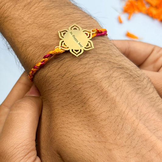 A person's wrist wearing the Engraved Mandala Rakhi with Multicolor Thread by Bliss Jouels, featuring a Be Happy Bro! engraving.