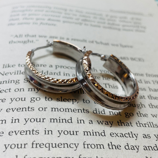 Alt text: Sunset Hoops: A pair of silver hoop earrings displayed on an open book, showcasing their simple yet versatile design.